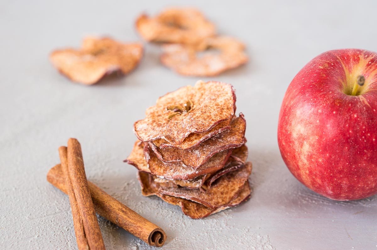 stacked apple chips next to an apple