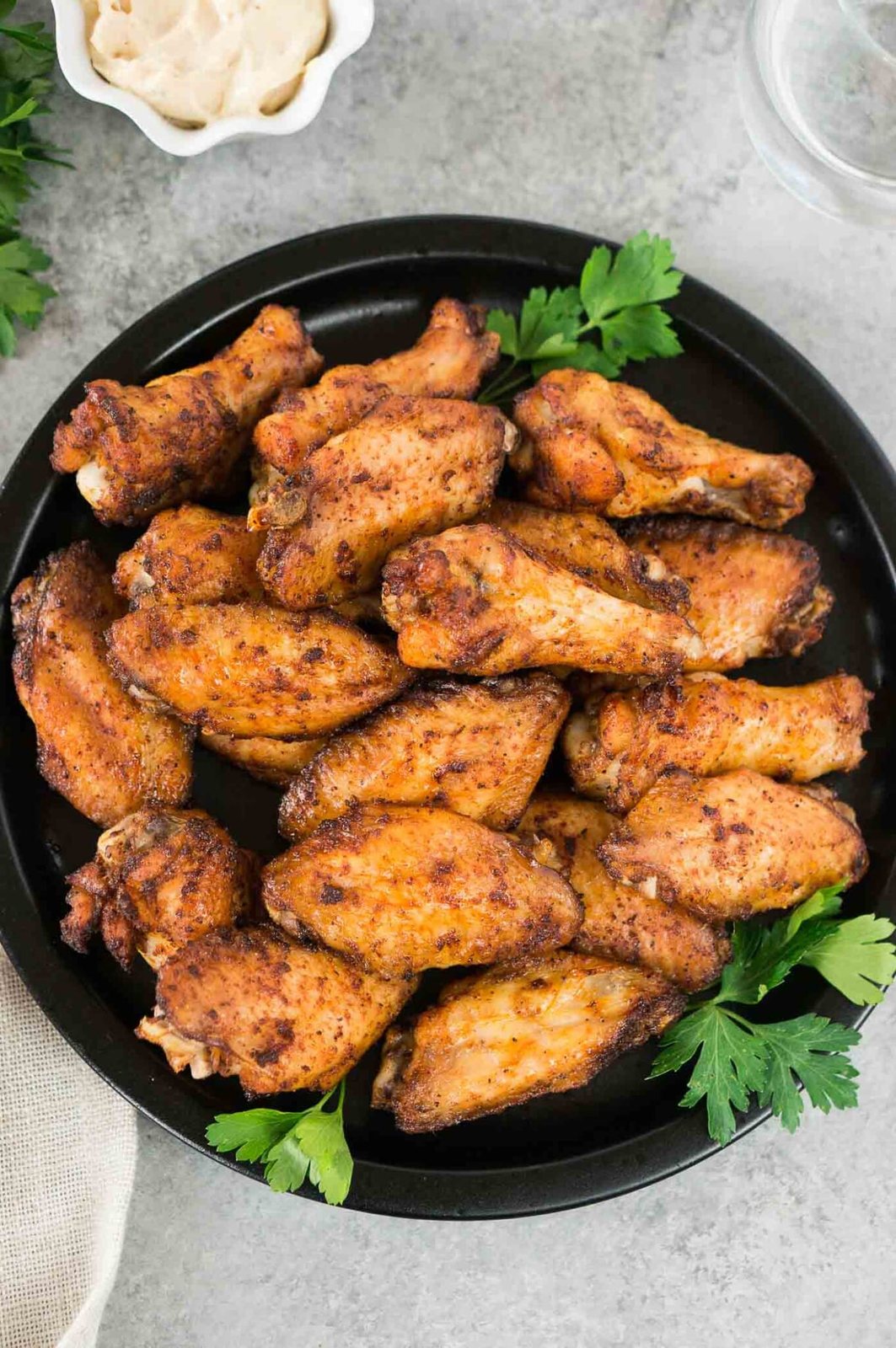 close up shot of crispy chicken wings on a plate with aioli sauce