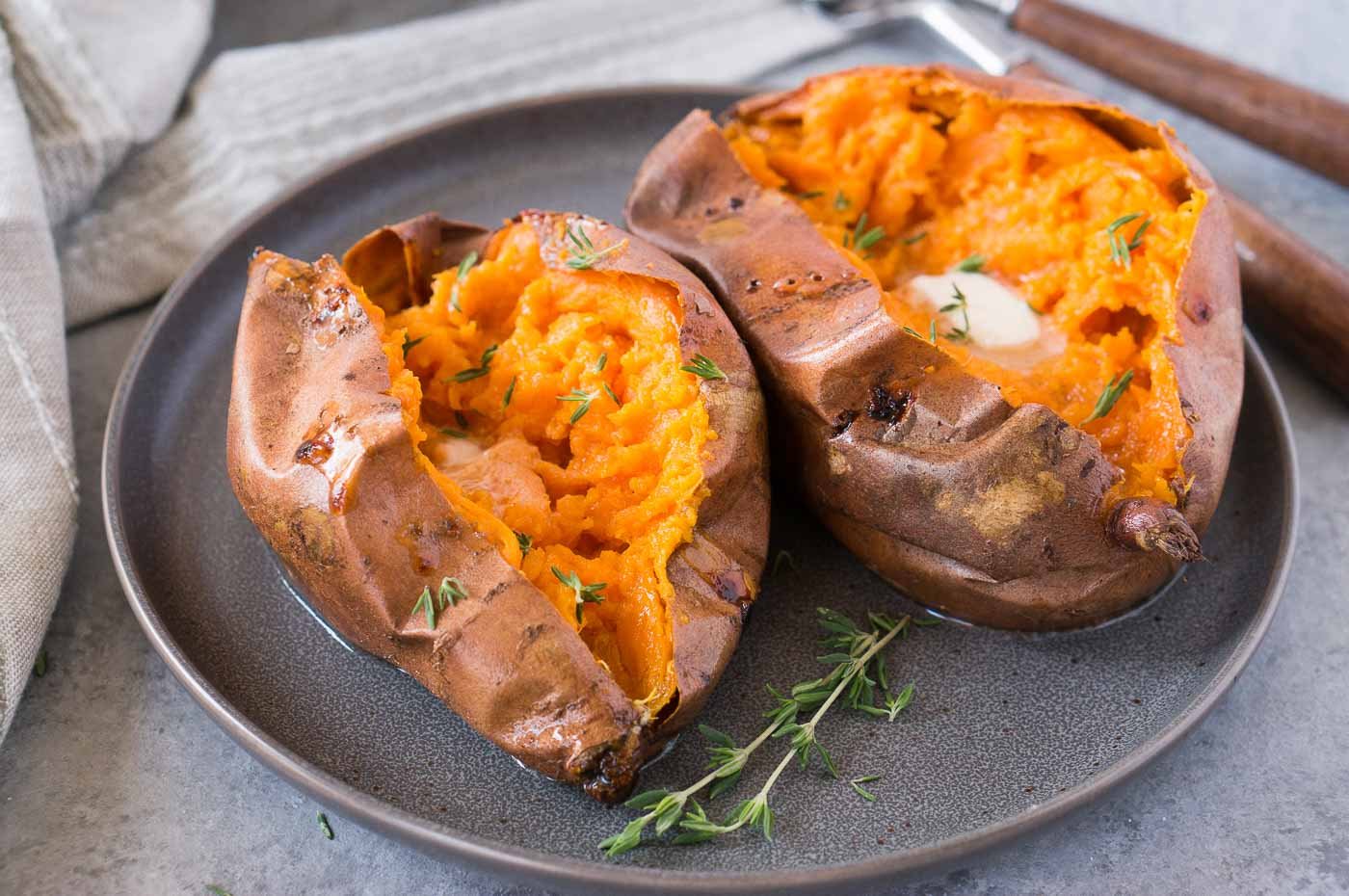 two sweet potatoes cut open and served with butter