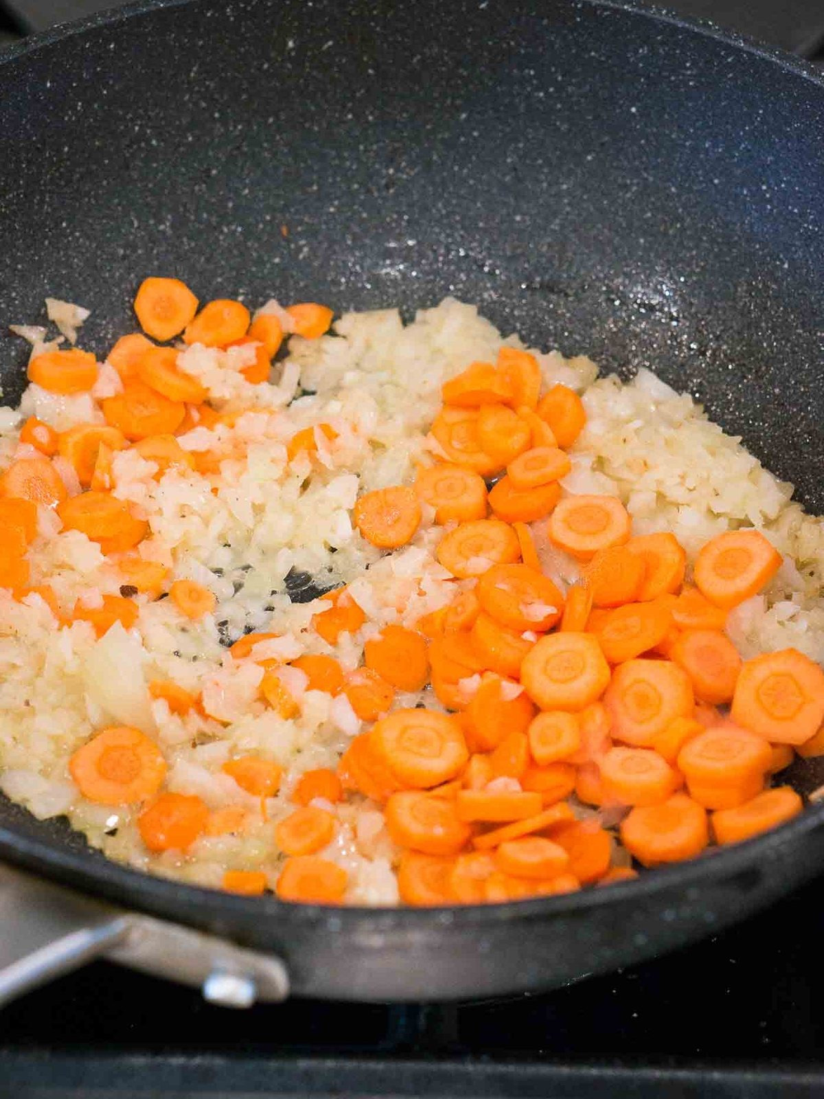 sauteing onions and carrots in a skillet