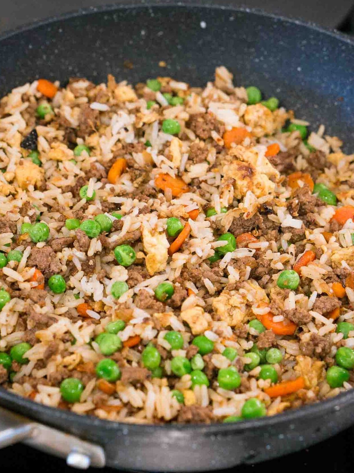 cooking ground beef and rice recipe with vegetables on the stove
