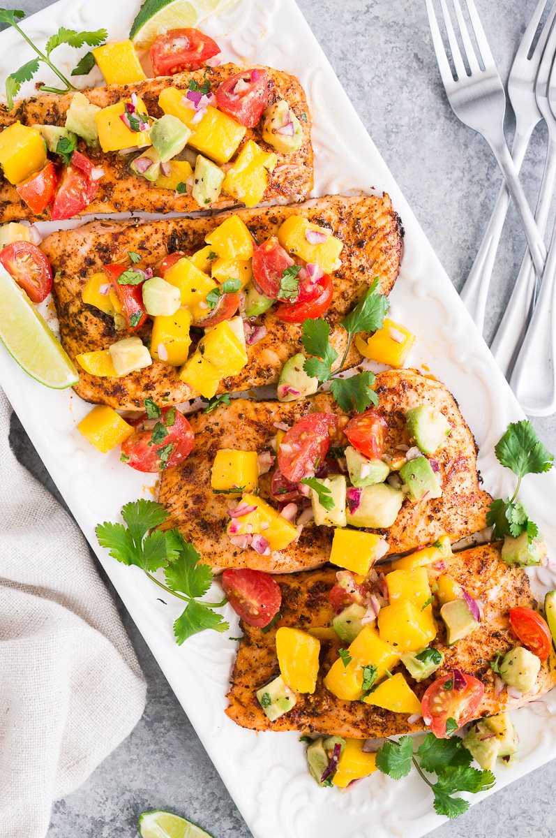 salmon fillets topped with mango avocado salsa on a platter