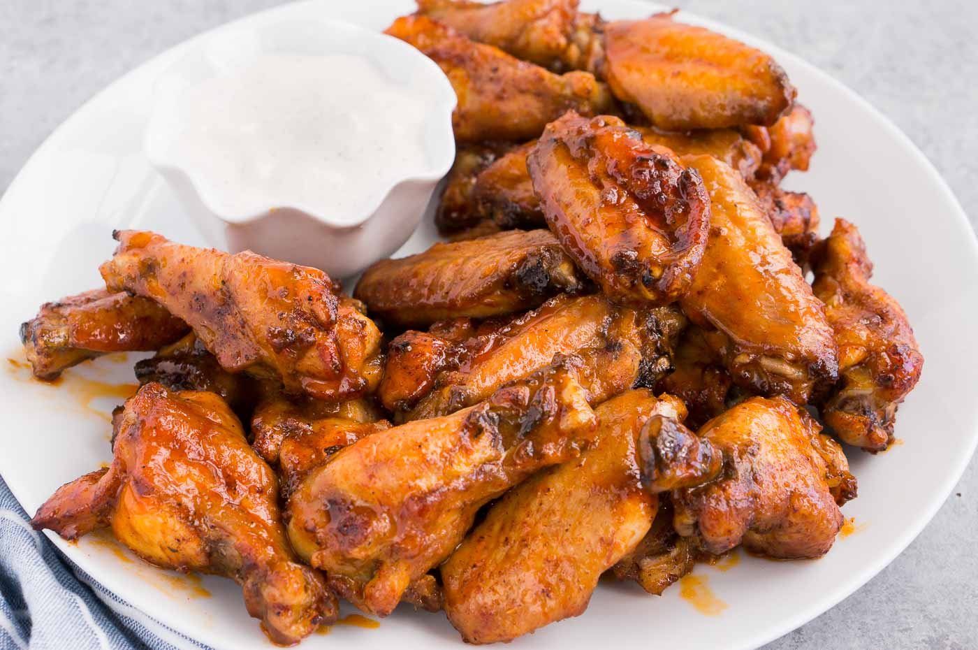 close up image of chicken wings and sauce on a plate