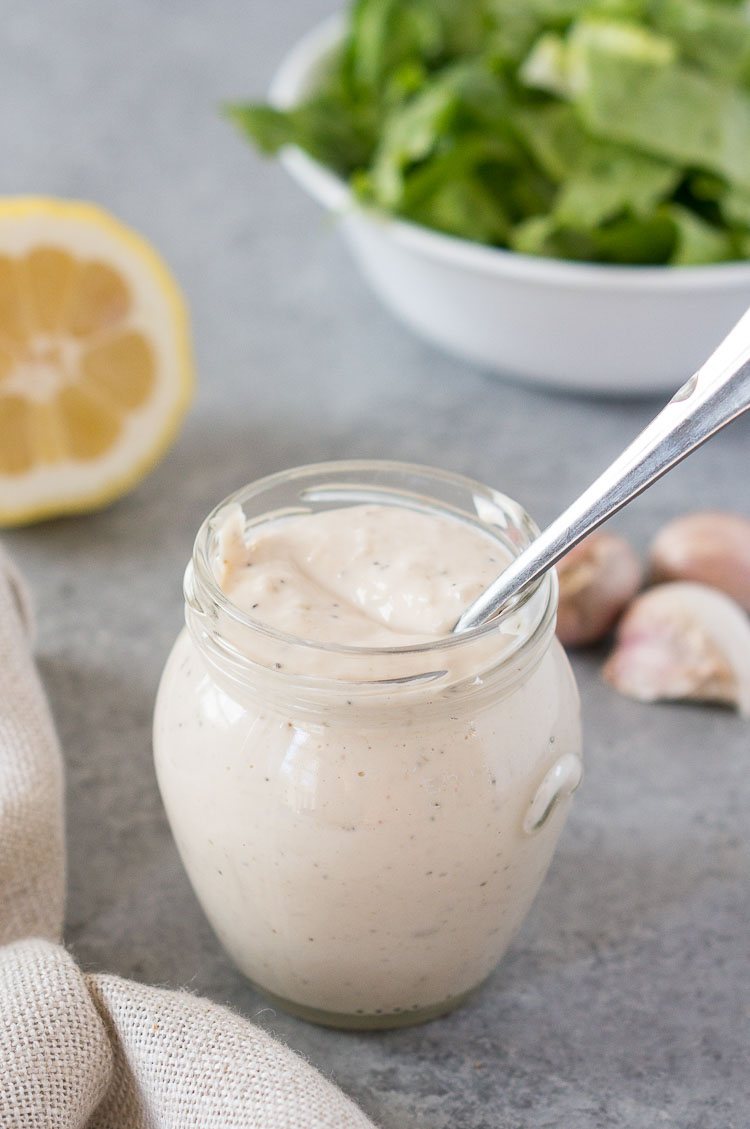healthy caesar salad dressing in a glass jar with a spoon inside
