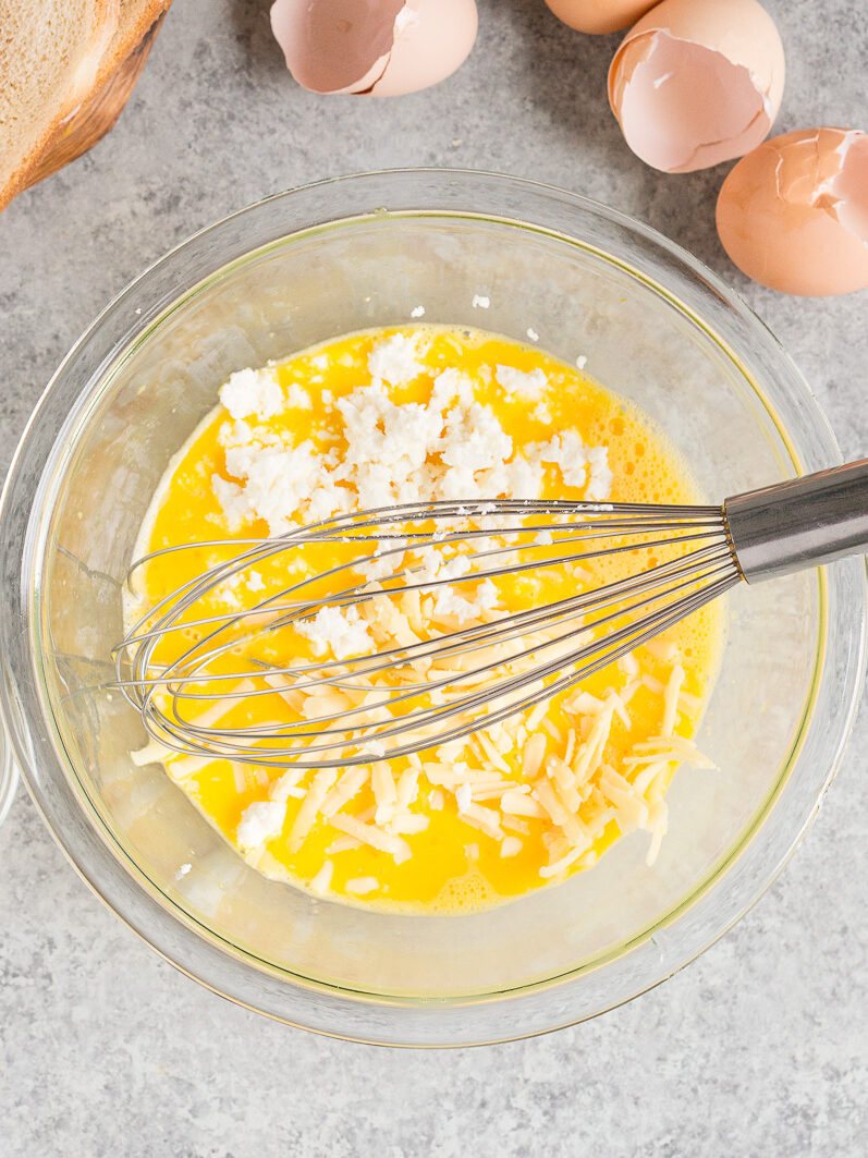 whisking eggs and cheese in a bowl