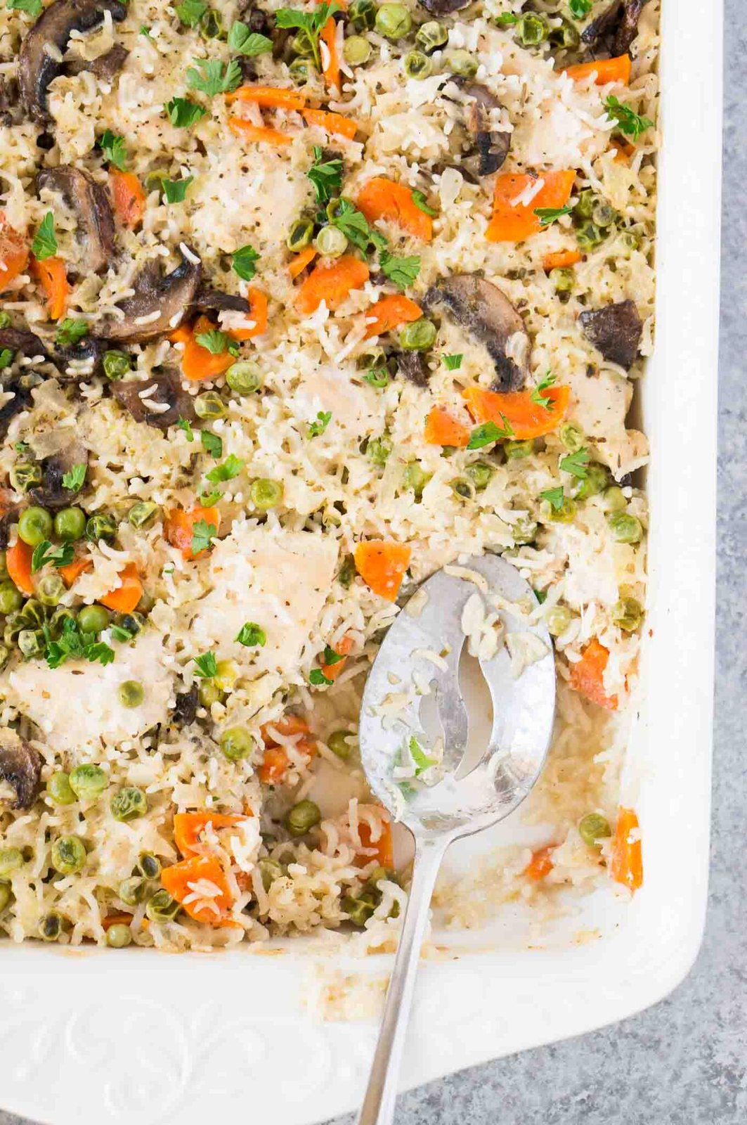 vegetables rice and chicken bake with a spoon in casserole dish