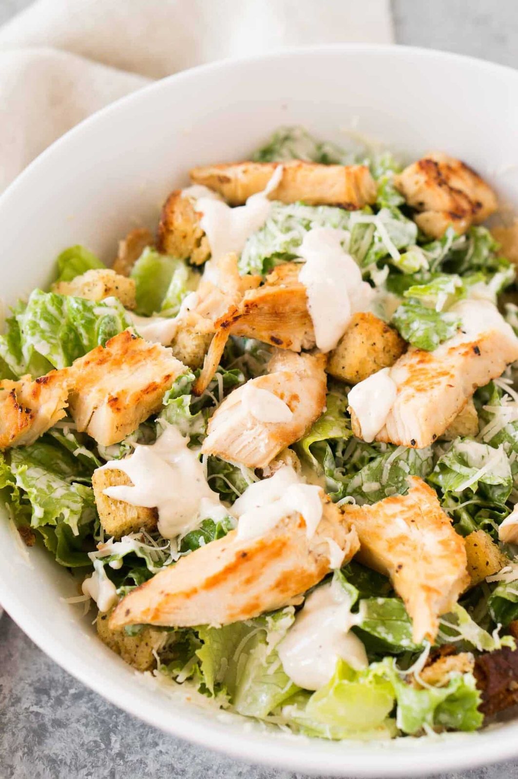 close up shot of Caesar salad with grilled chicken in a bowl