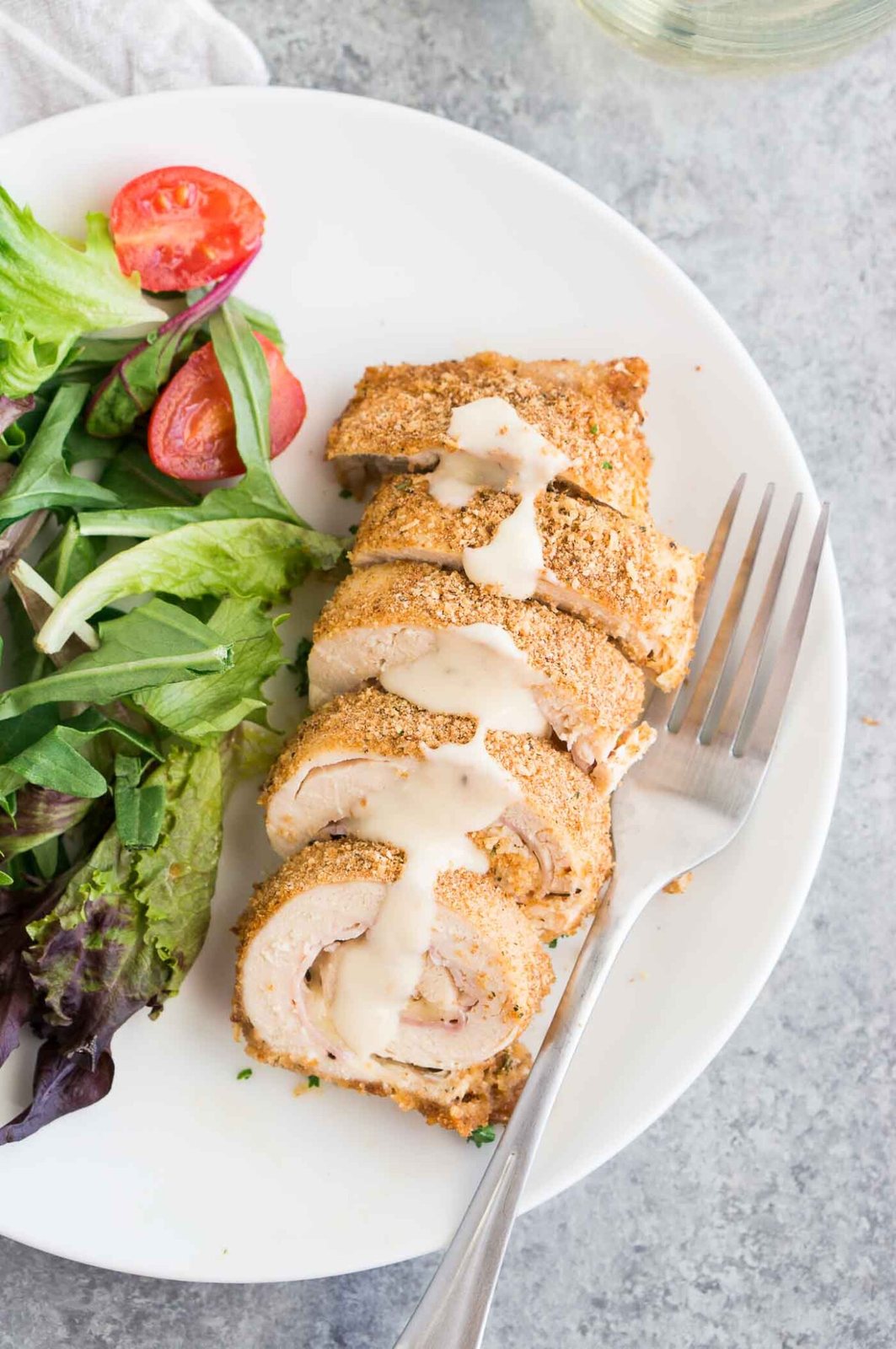 close up image of chicken stuffed with ham and cheese with Dijon sauce on a plate