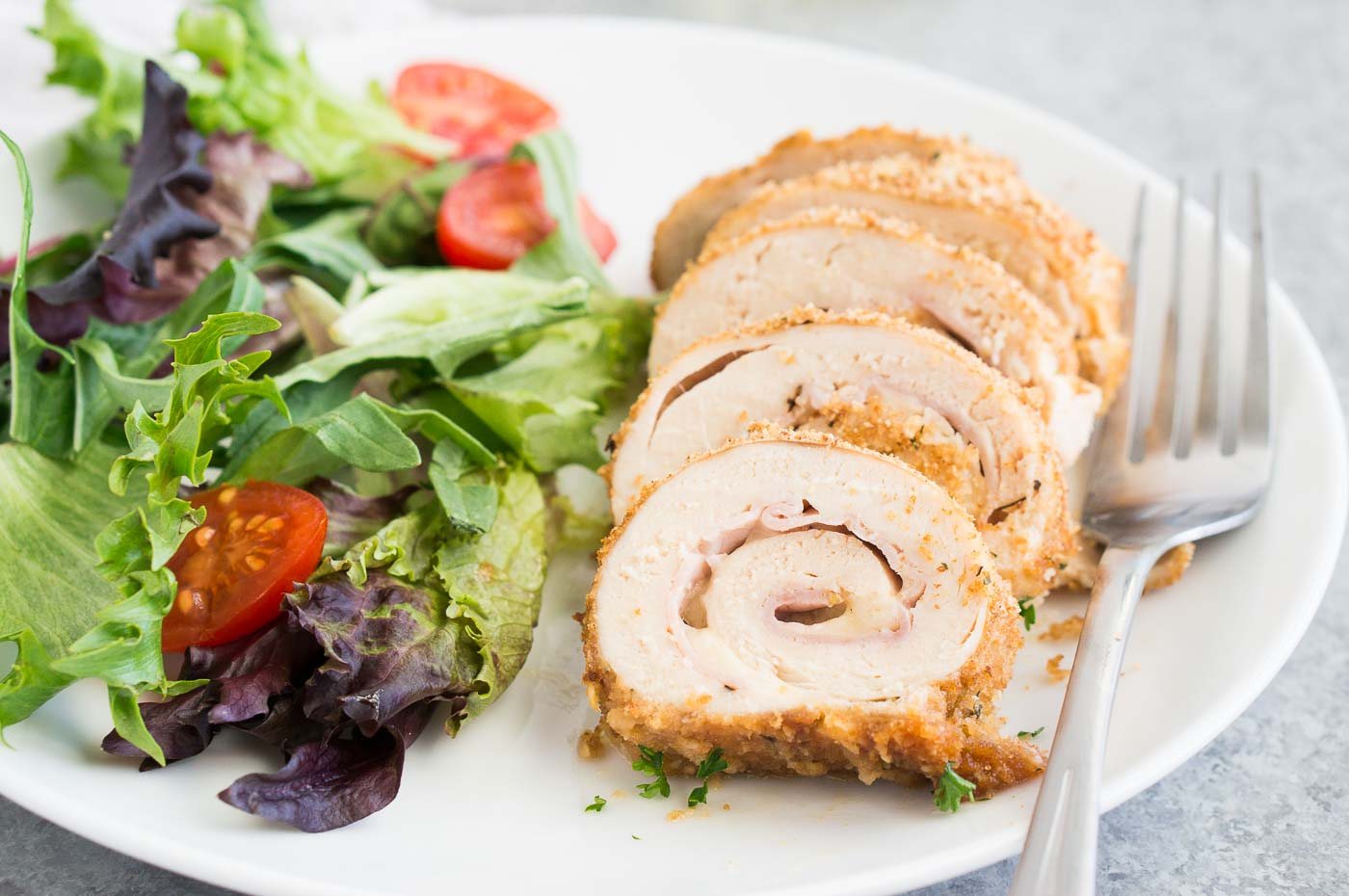 slices chicken with ham & cheese on a plate with salad