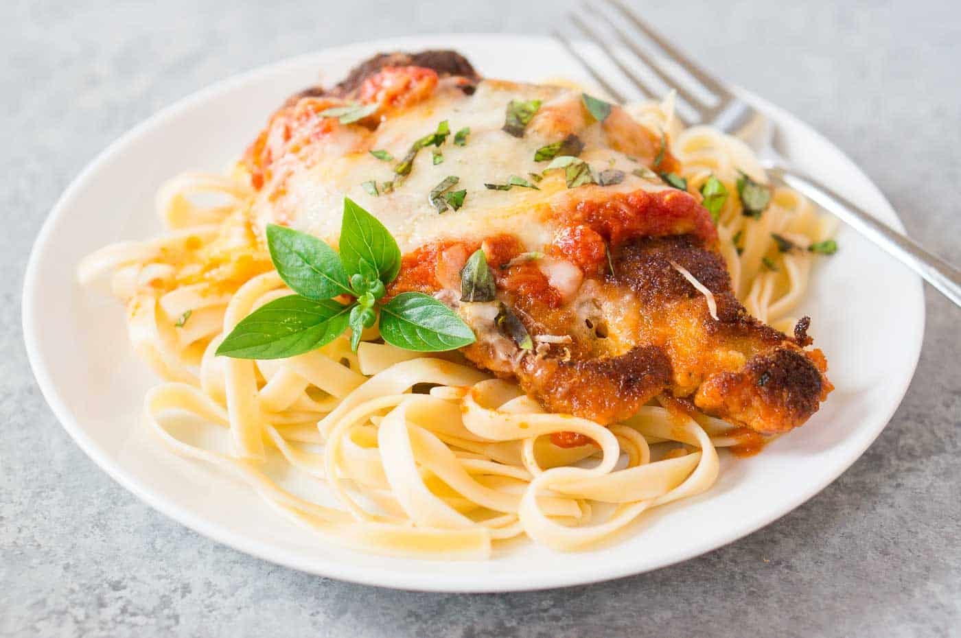 chicken parmesan over linguini pasta on a plate