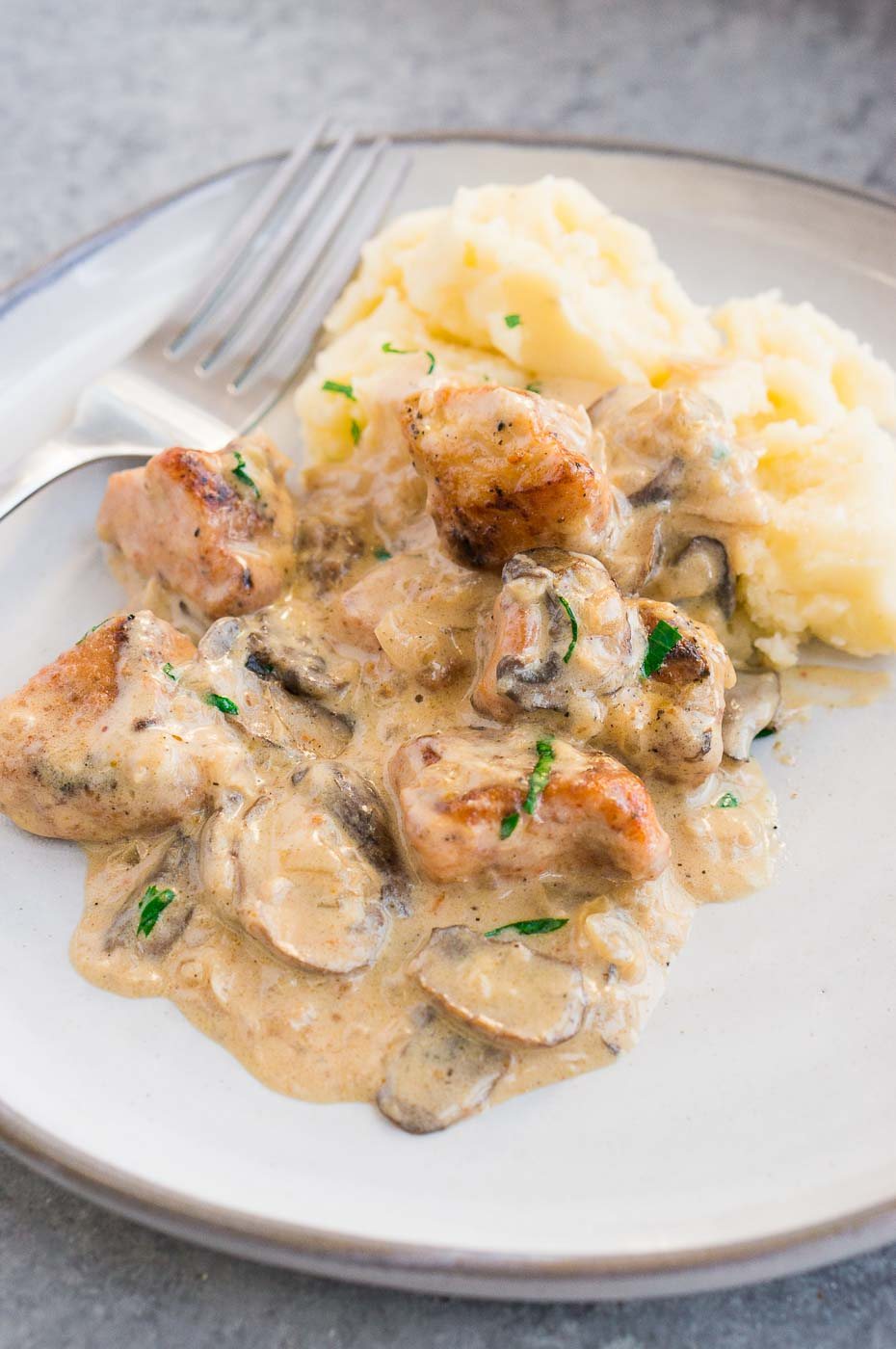 creamy mushroom chicken over mashed potatoes on a plate
