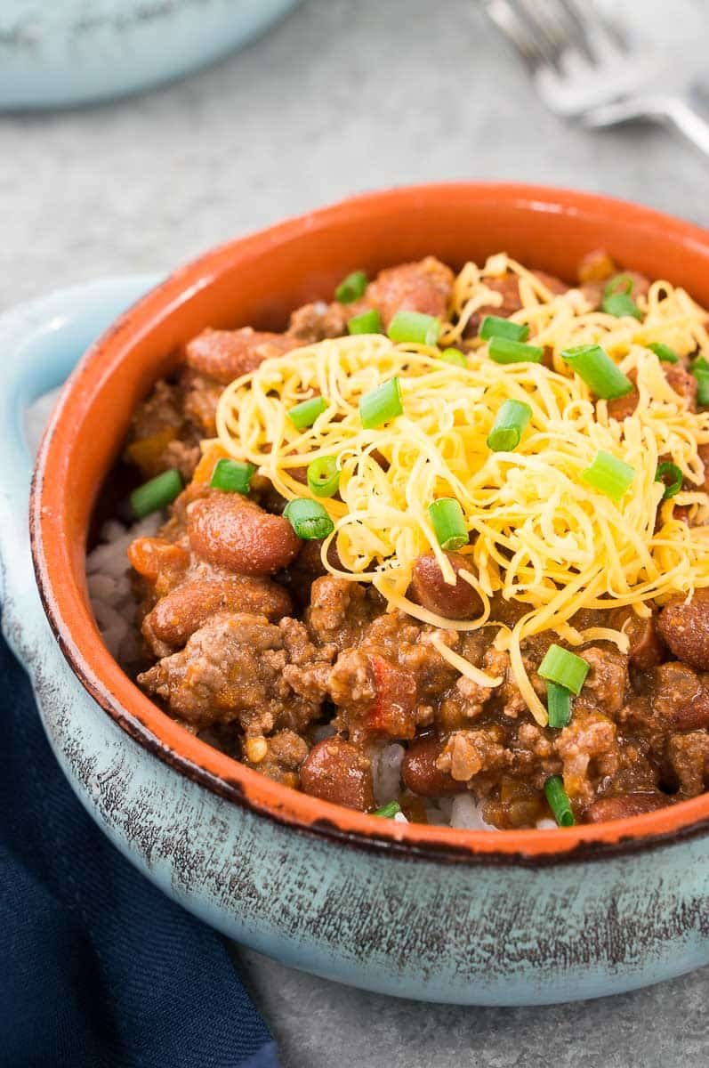 close up of chili recipe with shredded cheese and onions