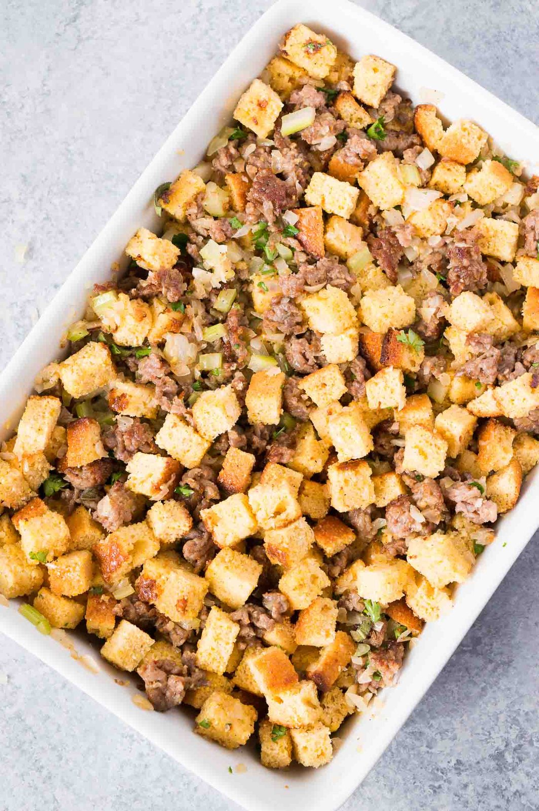 cornbread cubes with ground sausage and herbs in a casserole dish