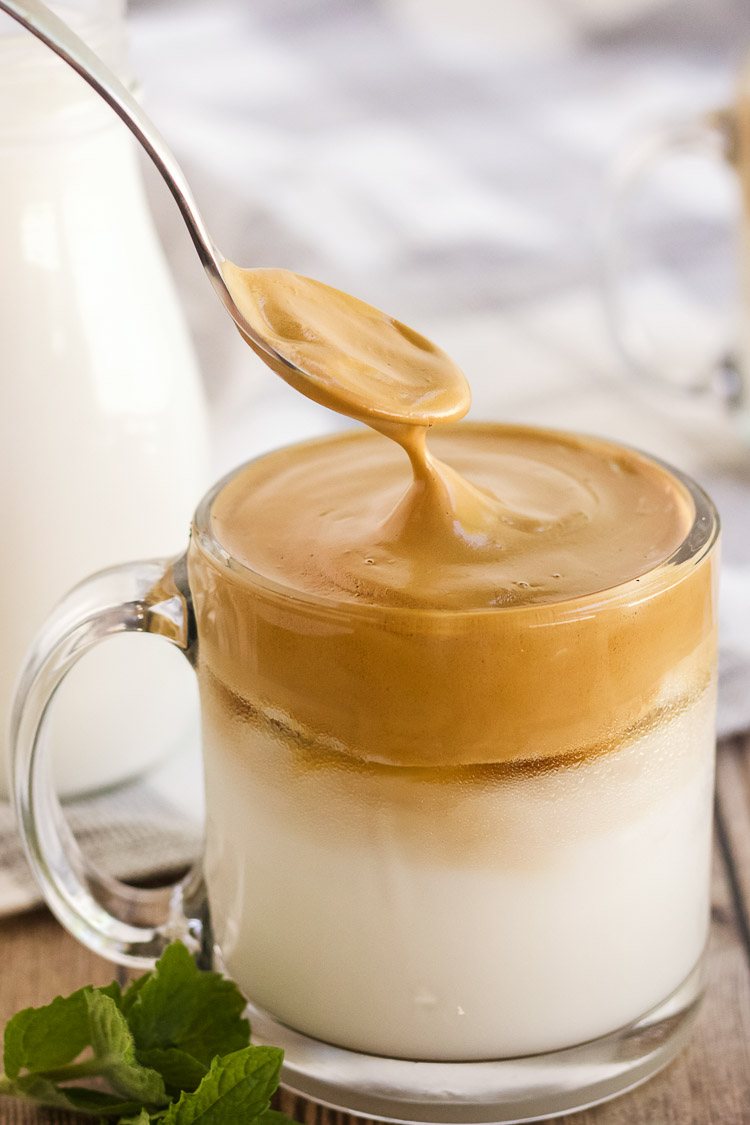 Spooning whipped coffee over cold milk