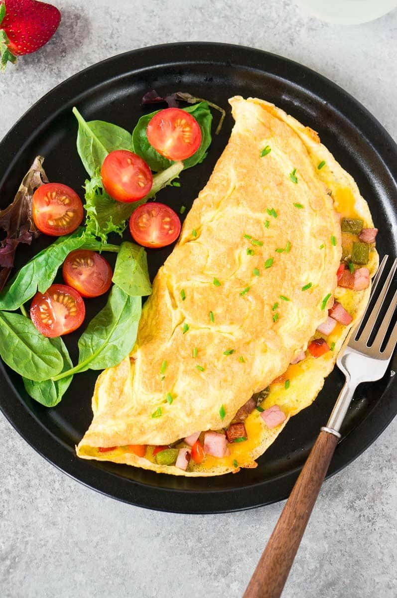 omelet for breakfast & greens on a black plate