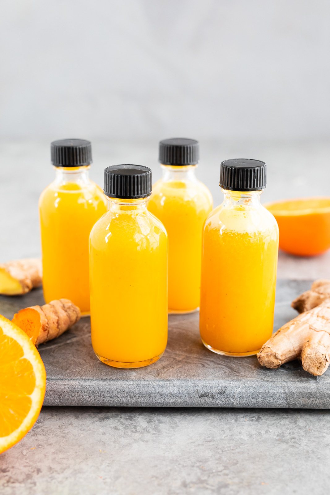 Bottles of homemade ginger turmeric shots made with fresh ginger, turmeric, and citrus