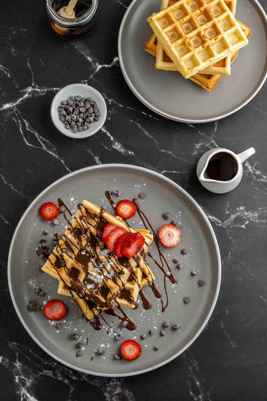 waffles topped with sliced strawberries and melted chocolate