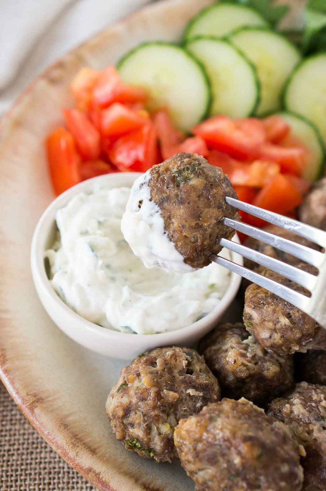 dipping keftedes in tzatziki sauce