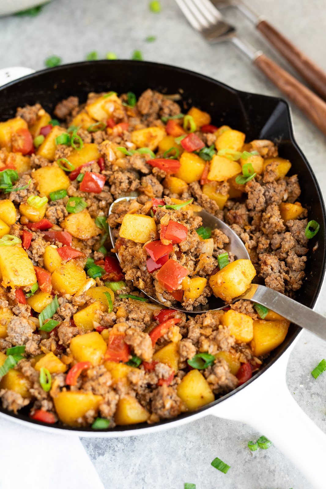 scooping beef and potatoes from a skillet