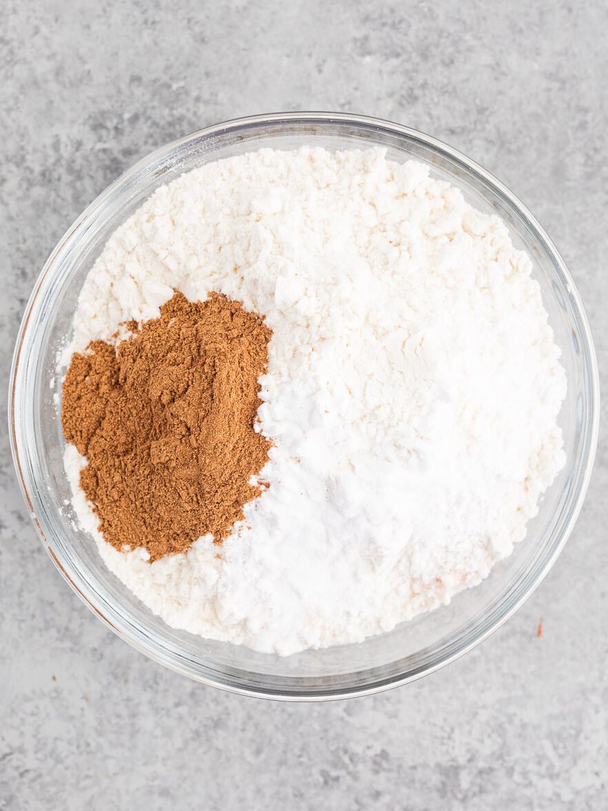 Mixing flour with pumpkin spice and baking powder and baking soda in a bowl