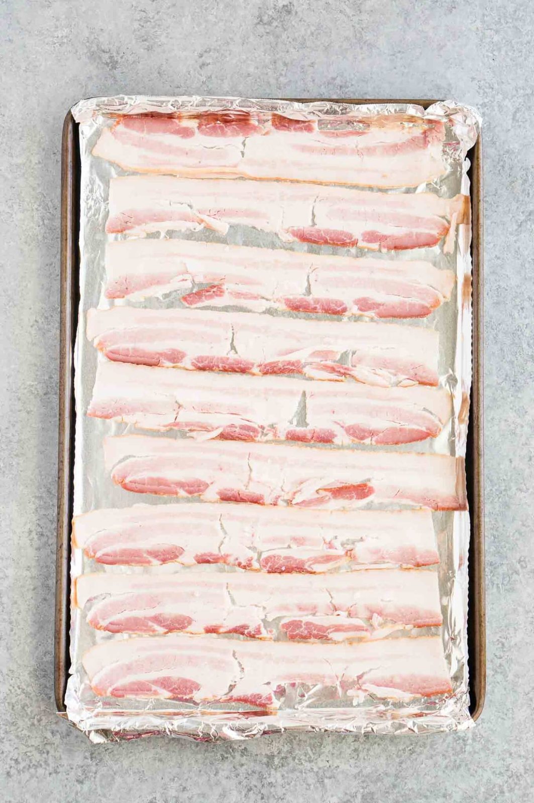 raw bacon on baking sheet with aluminum foil