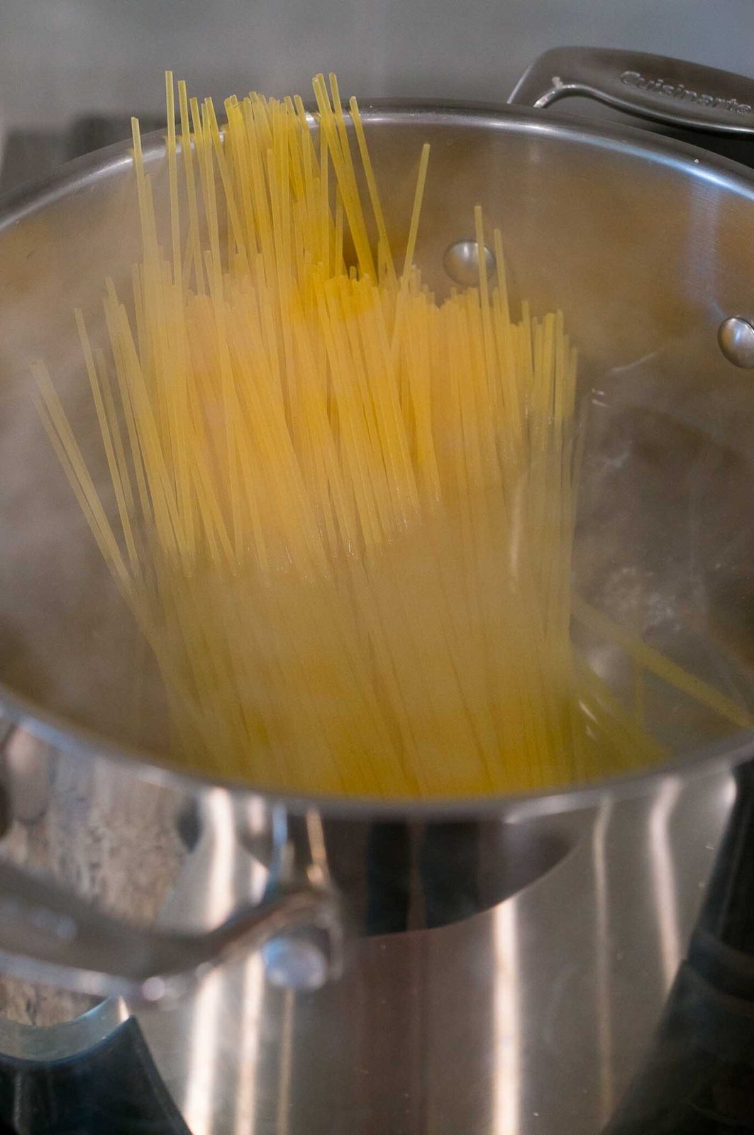 adding dry pasta to a pot with boiling water