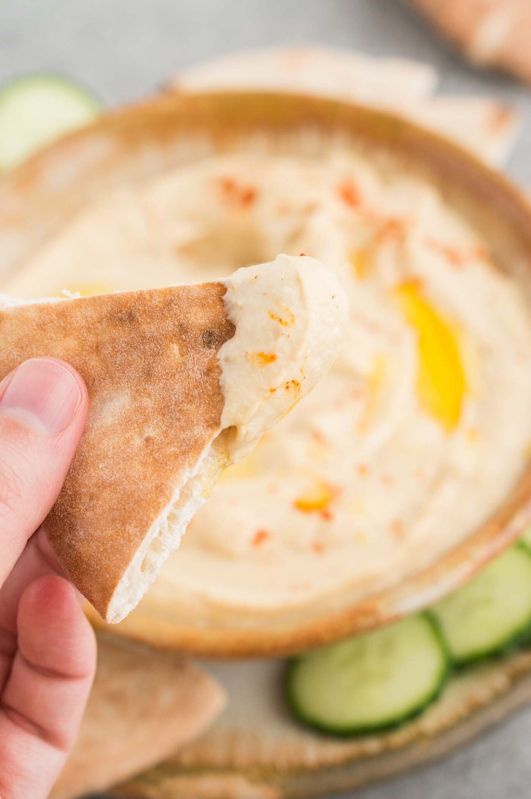 close up image of hummus in a bowl and slice of pita