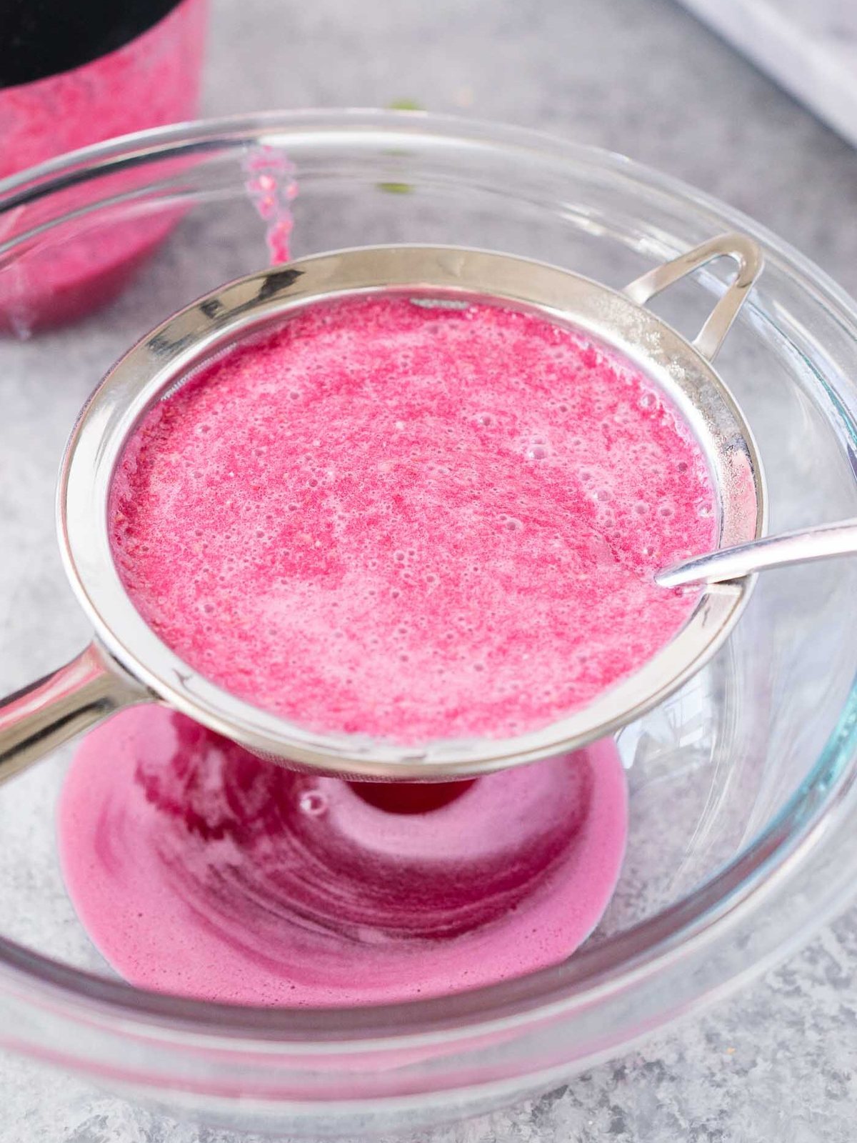 straining pomegranate juice through a strainer