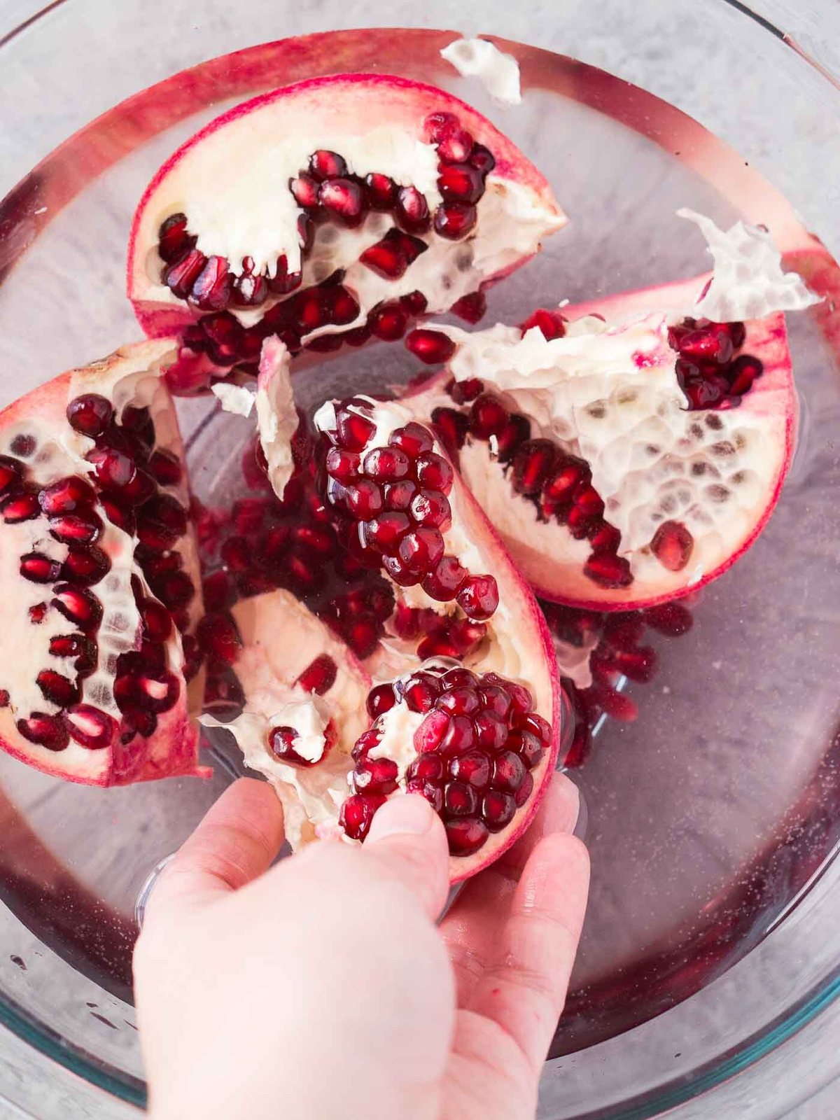 removing pomegranate arils in a bowl with water