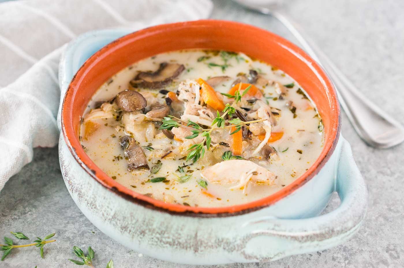 close up image of chicken wild rice soup in a clay bowl