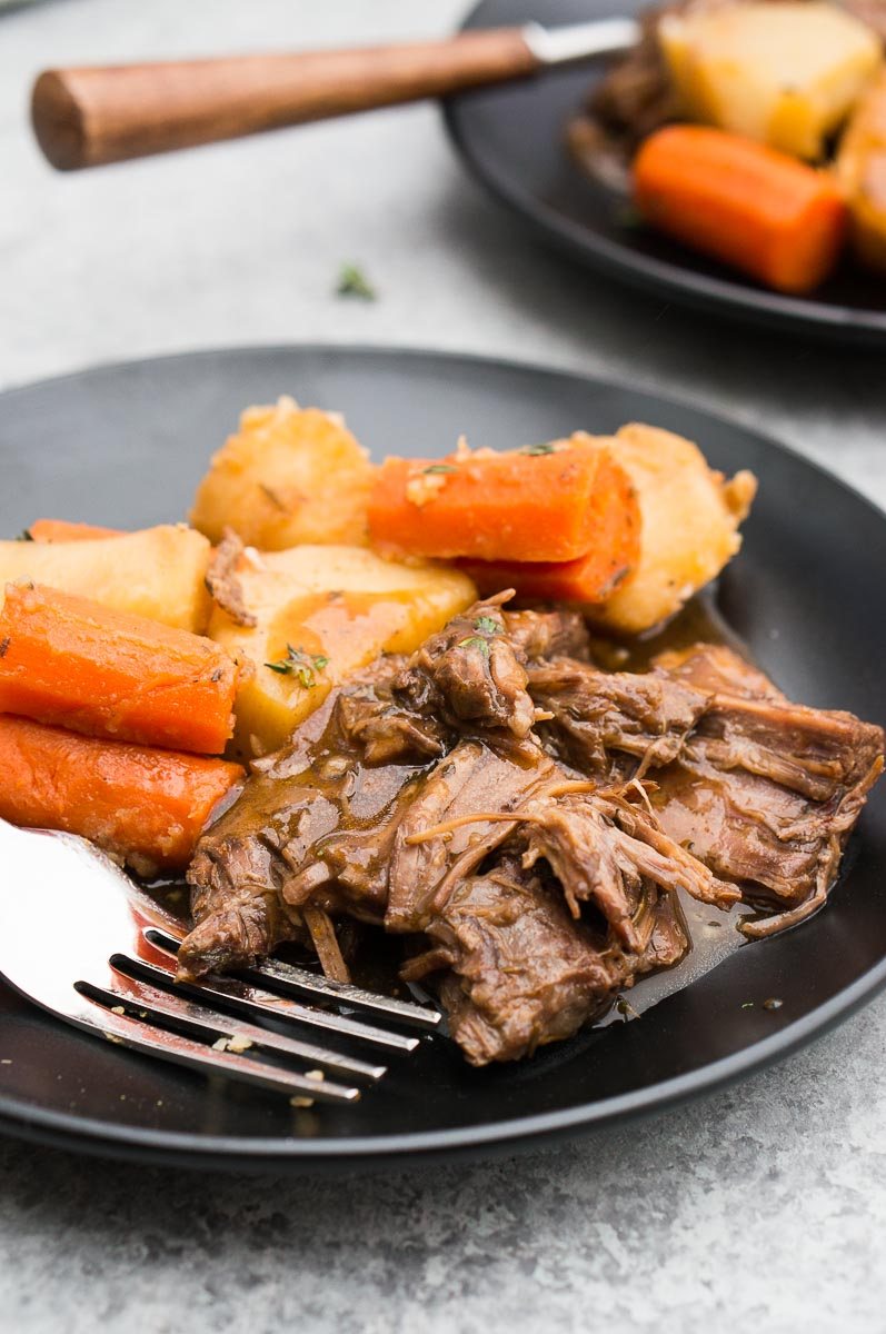 pressure cooker pot roast served on a black plate with a fork