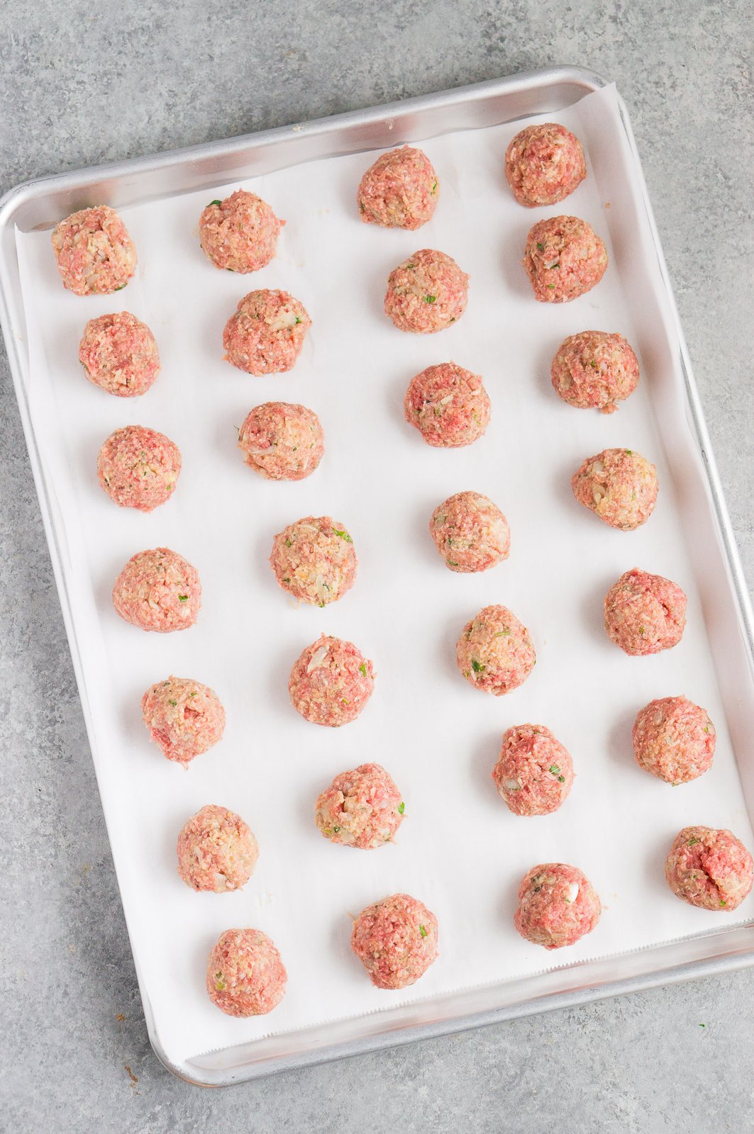 formed raw meatballs on a baking sheet