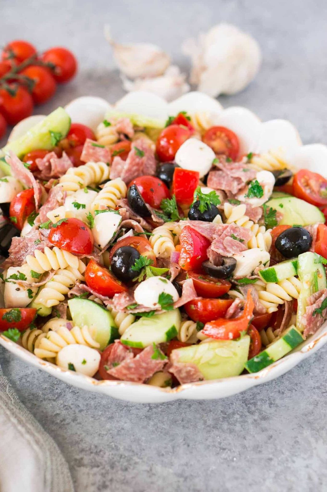 Pasta salad with mozzarella salami tomatoes and cucumbers in a bowl