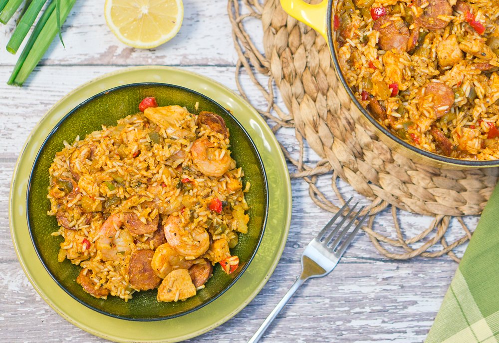 A bowl of jambalaya next to a dutch oven