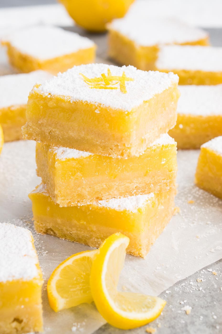 sliced lemon squares and a lemon slice on parchment paper