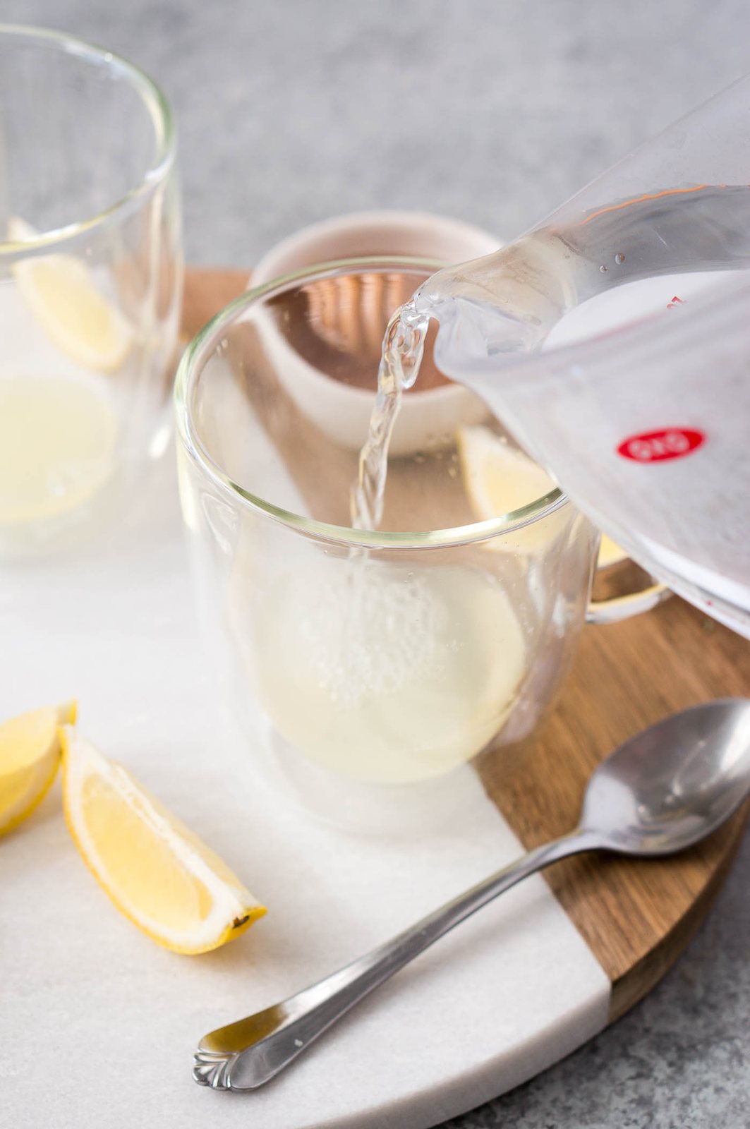 adding warm water to glass cup with lemon juice