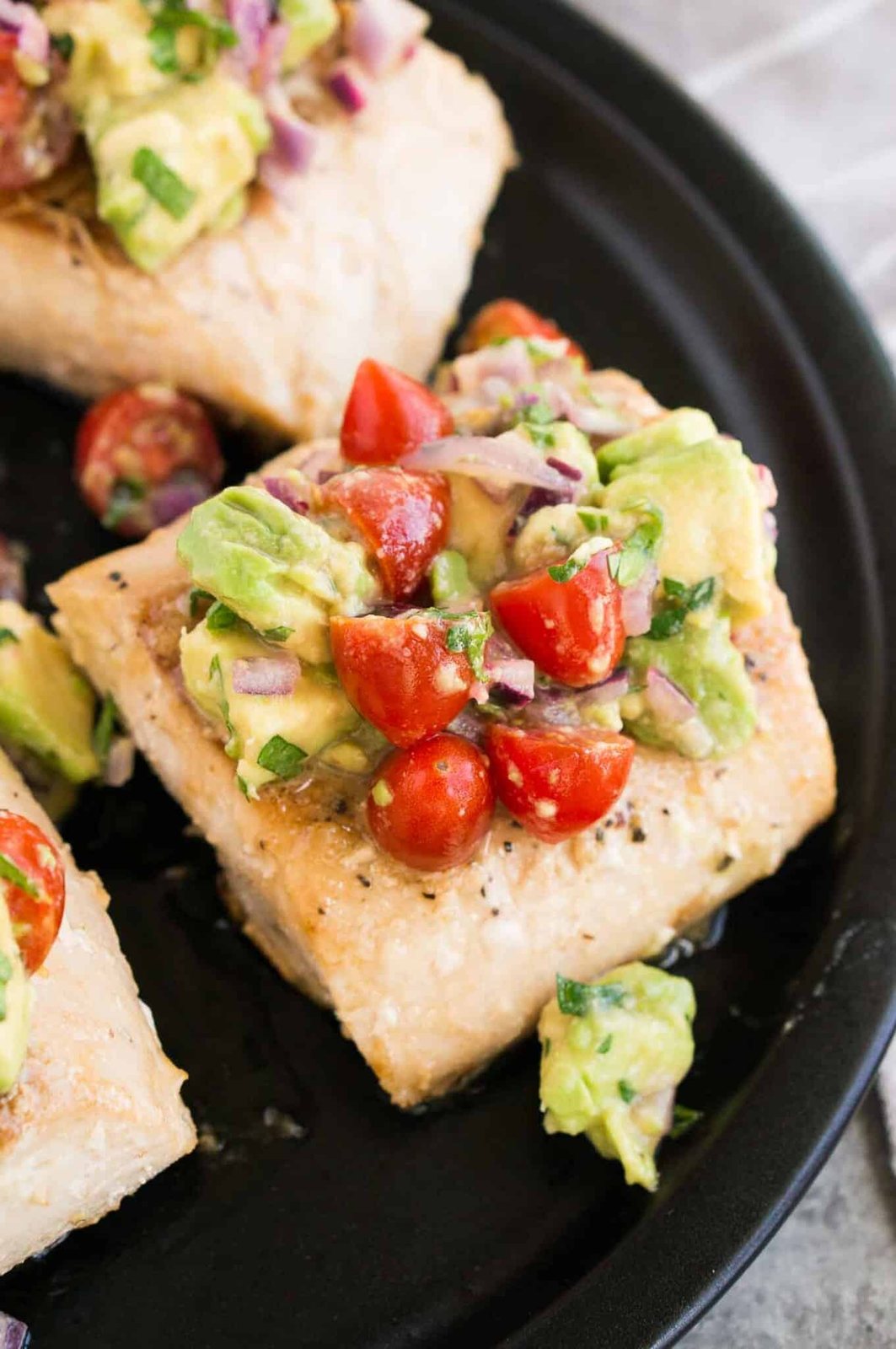 close up image of mahi mahi topped with avocado salsa on a plate