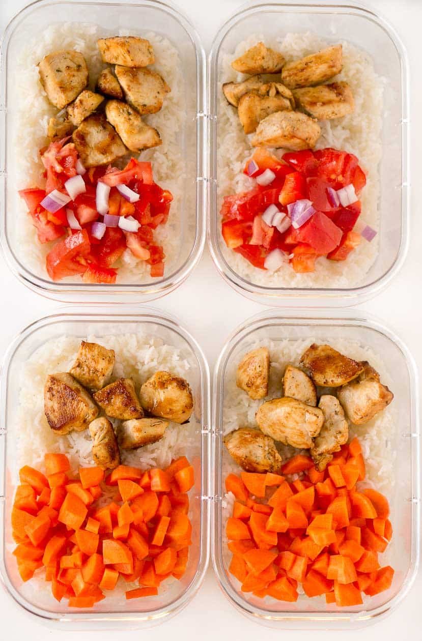 A plastic container filled with chicken rice and vegetables