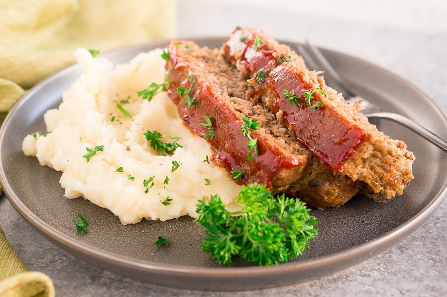classic meatloaf sliced on a plate with mashed potatoes