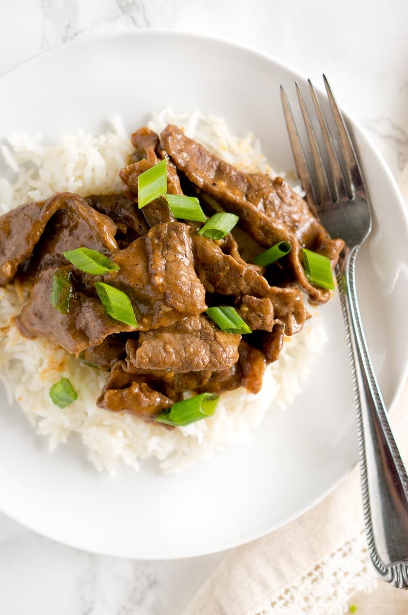Mongolian beef with a fork on a plate served over rice