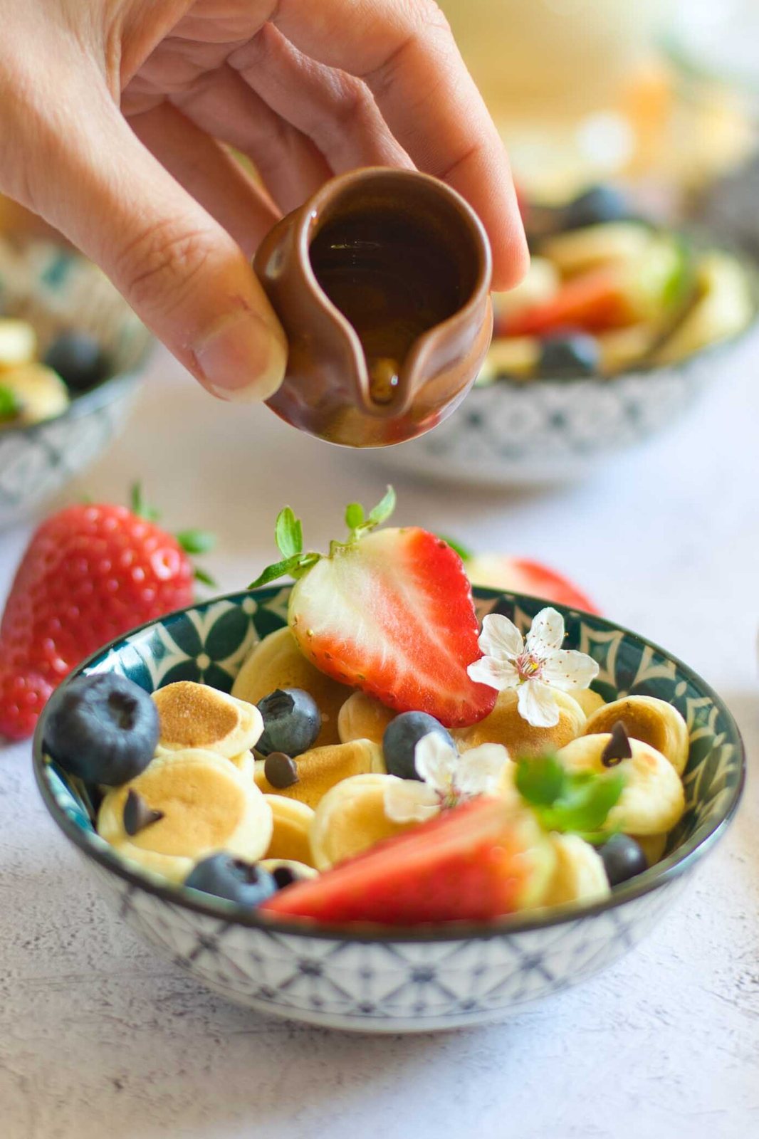 pouring maple syrup over pancake cereal in a bowl
