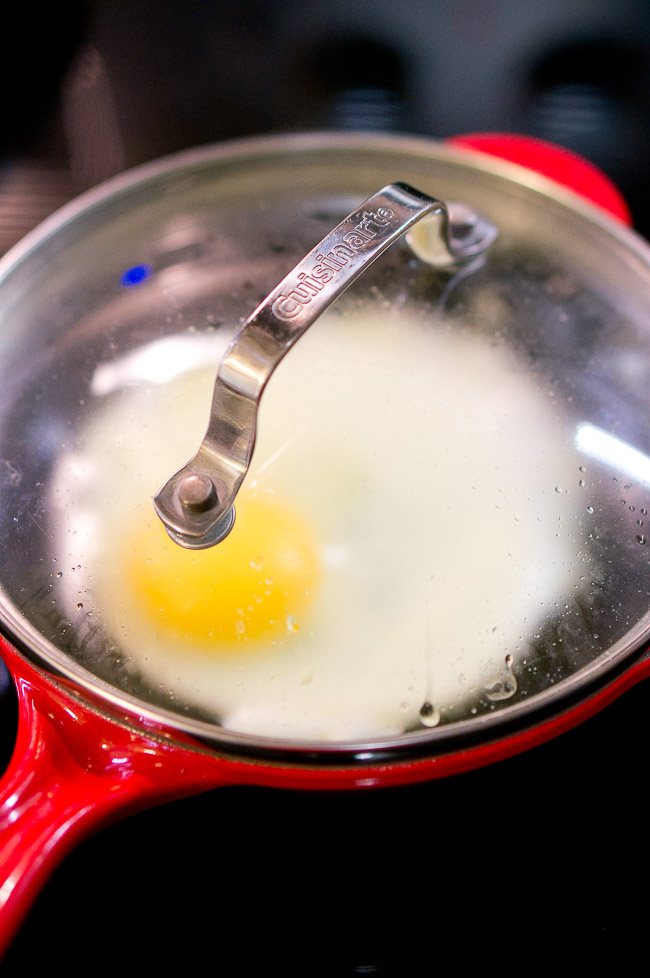 An egg cooking in a pan with a lid