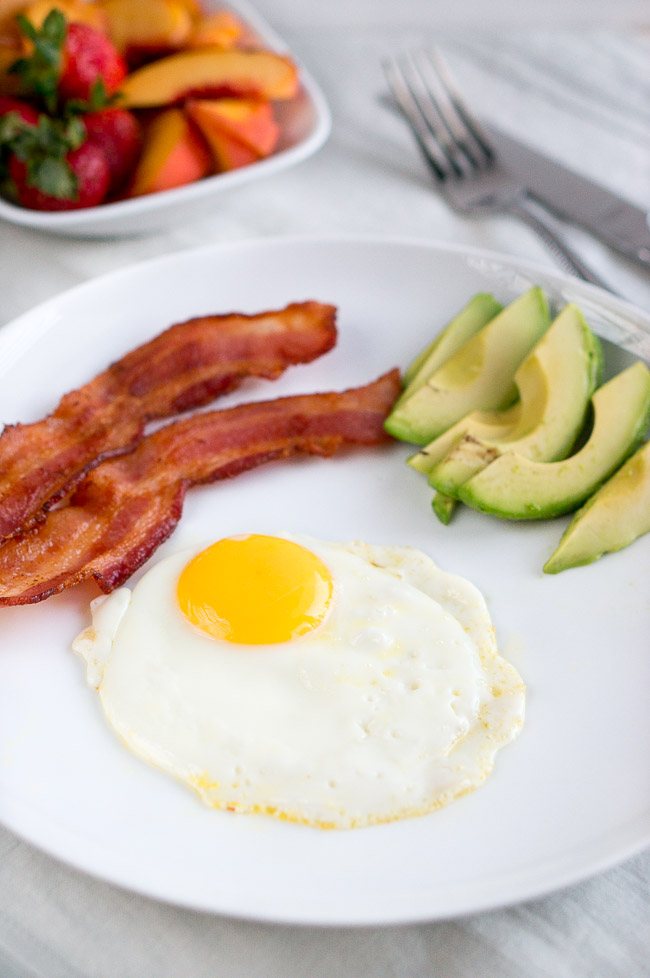 A fried egg served with bacon and avocado