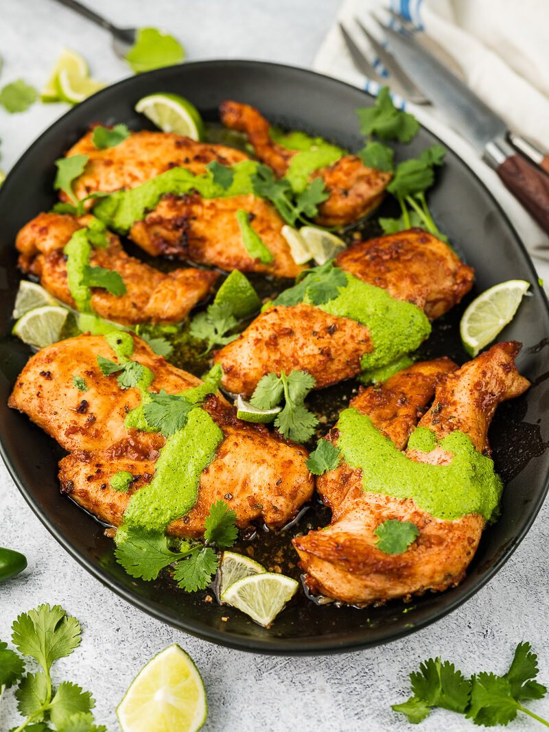 peruvian chicken breast with green sauce on a platter