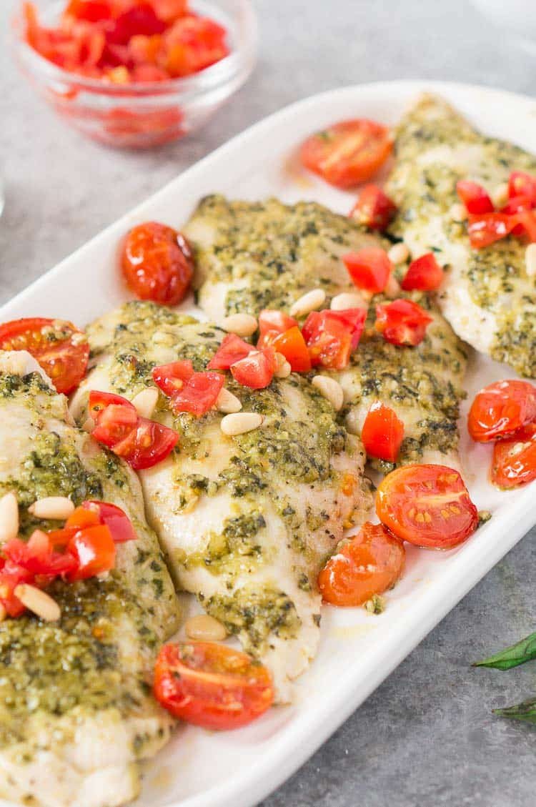 close up shot of basil pesto chicken on a white plate