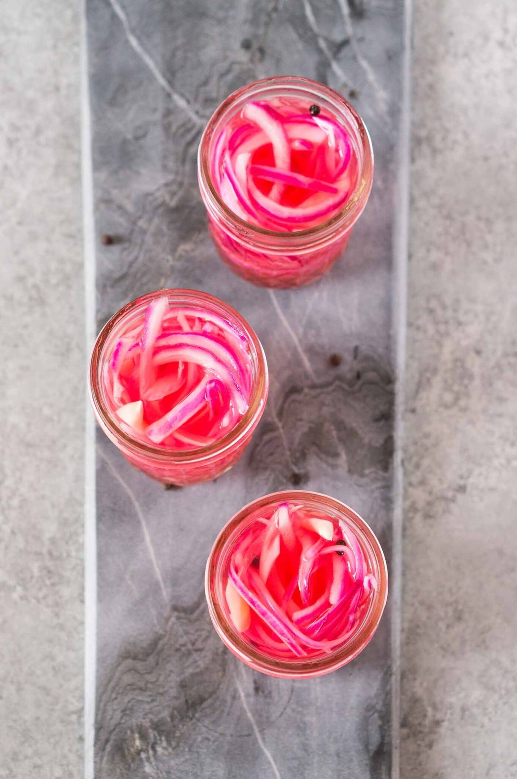 pickled red onions on a gray board