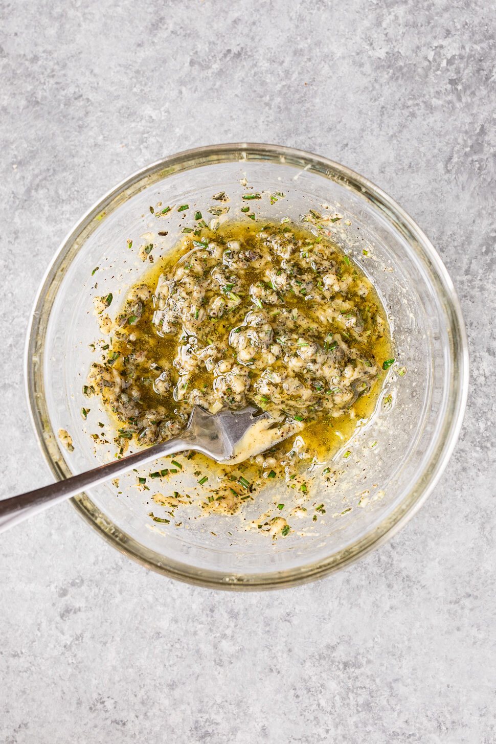 Garlic, rosemary, thyme, olive oil, and Dijon mustard mixed together to make the herb rub for roasted leg of lamb.