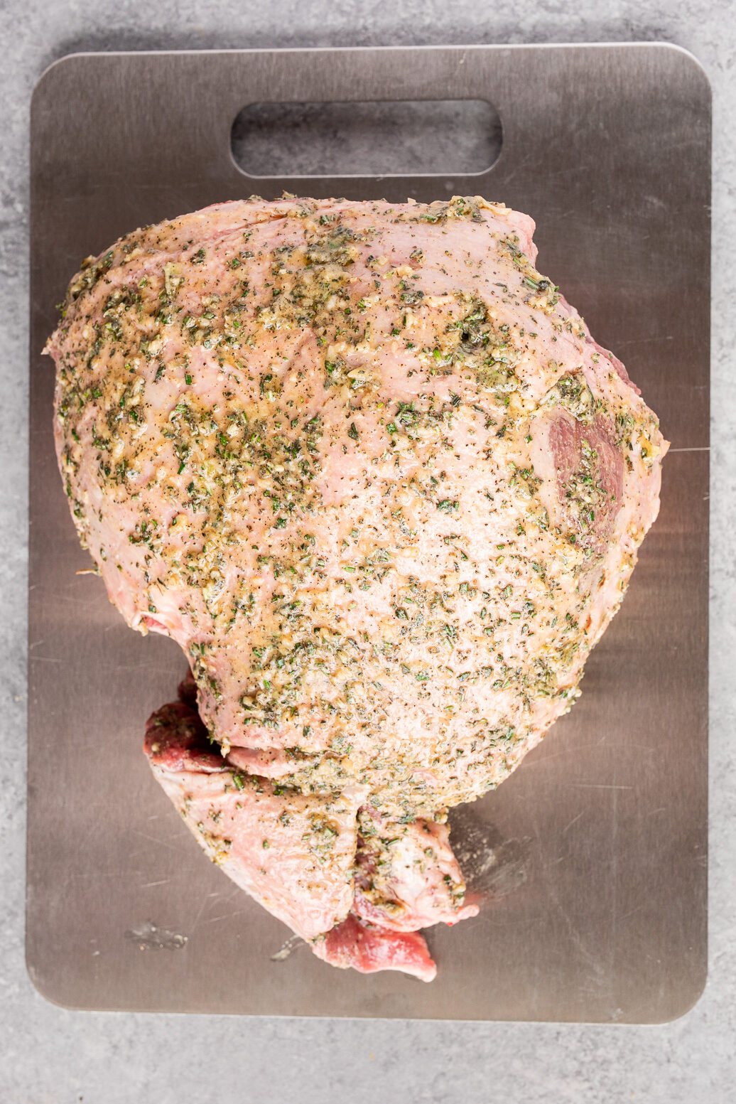 Boneless leg of lamb coated with garlic, rosemary, and thyme herb rub before roasting