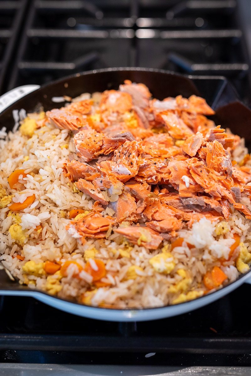 cooking fried rice with salmon in a skillet