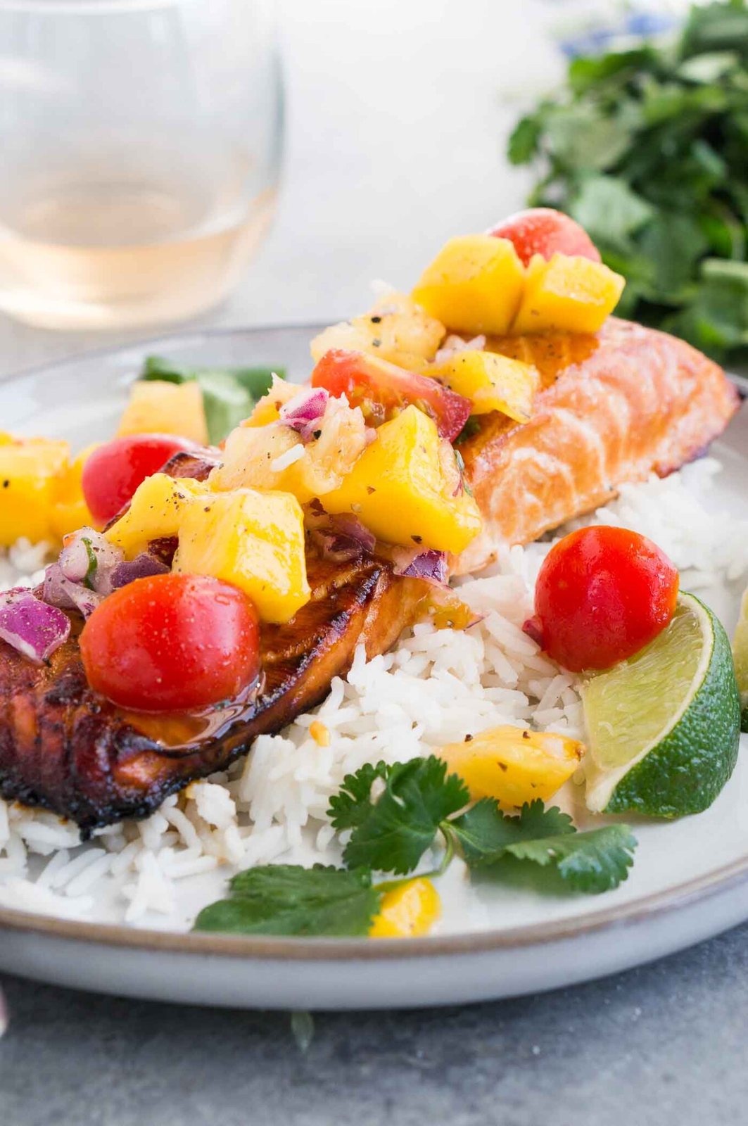 close up image of honey salmon with mango salsa over rice